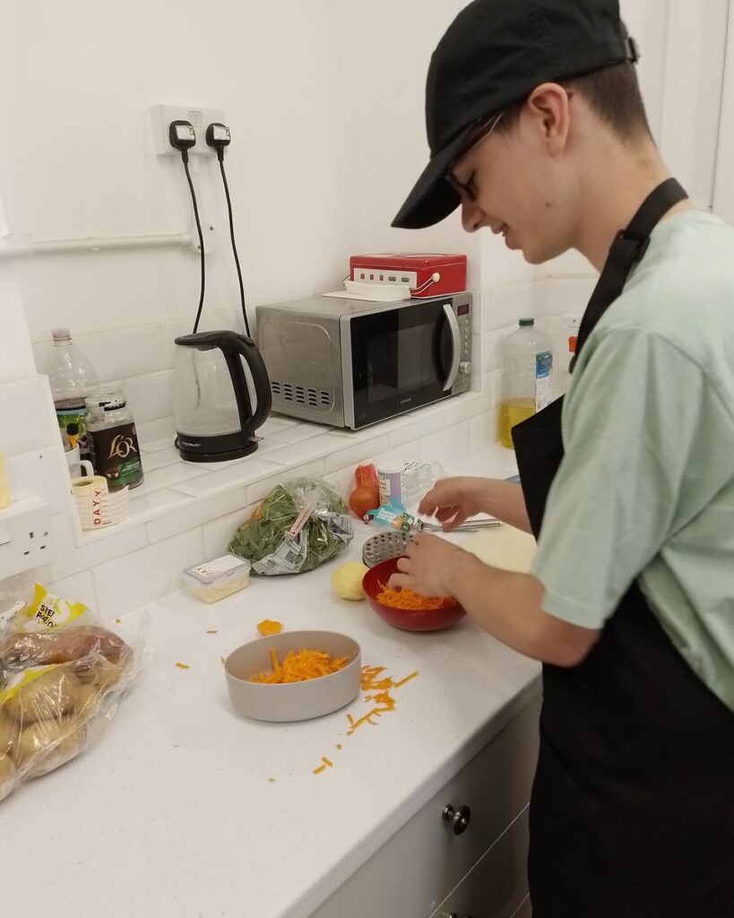 Felix grating carrots as part of a recipe he's making.