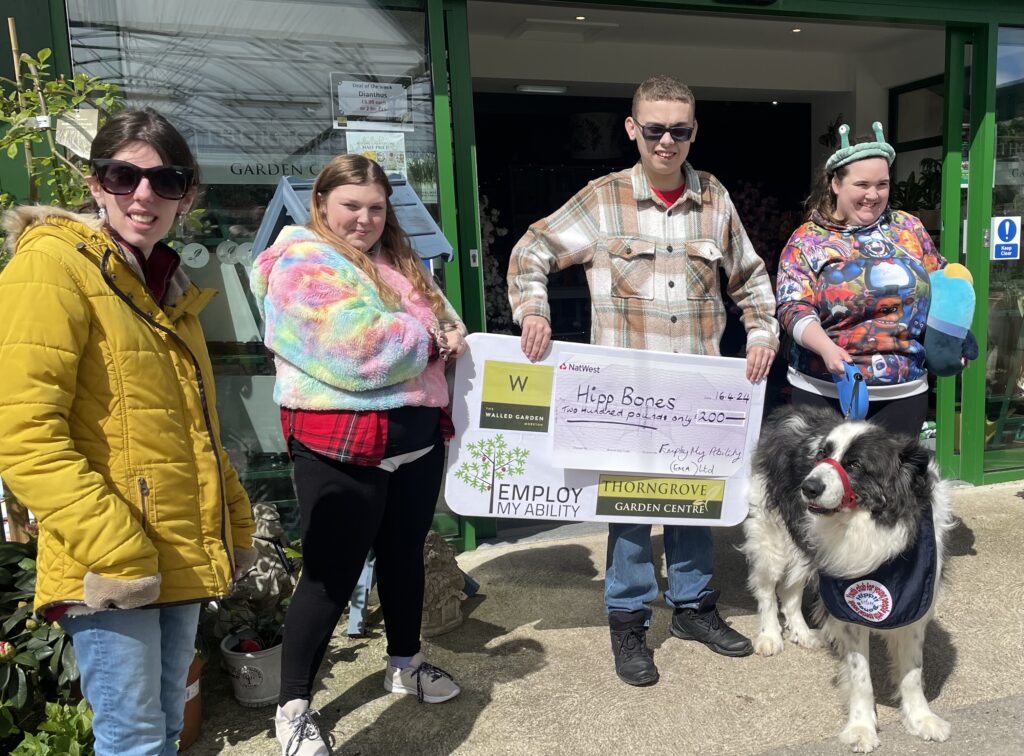 A group gillingham students and a tutor and a dog outside the Thorngrove Garden Centre with a NatWest achievement.