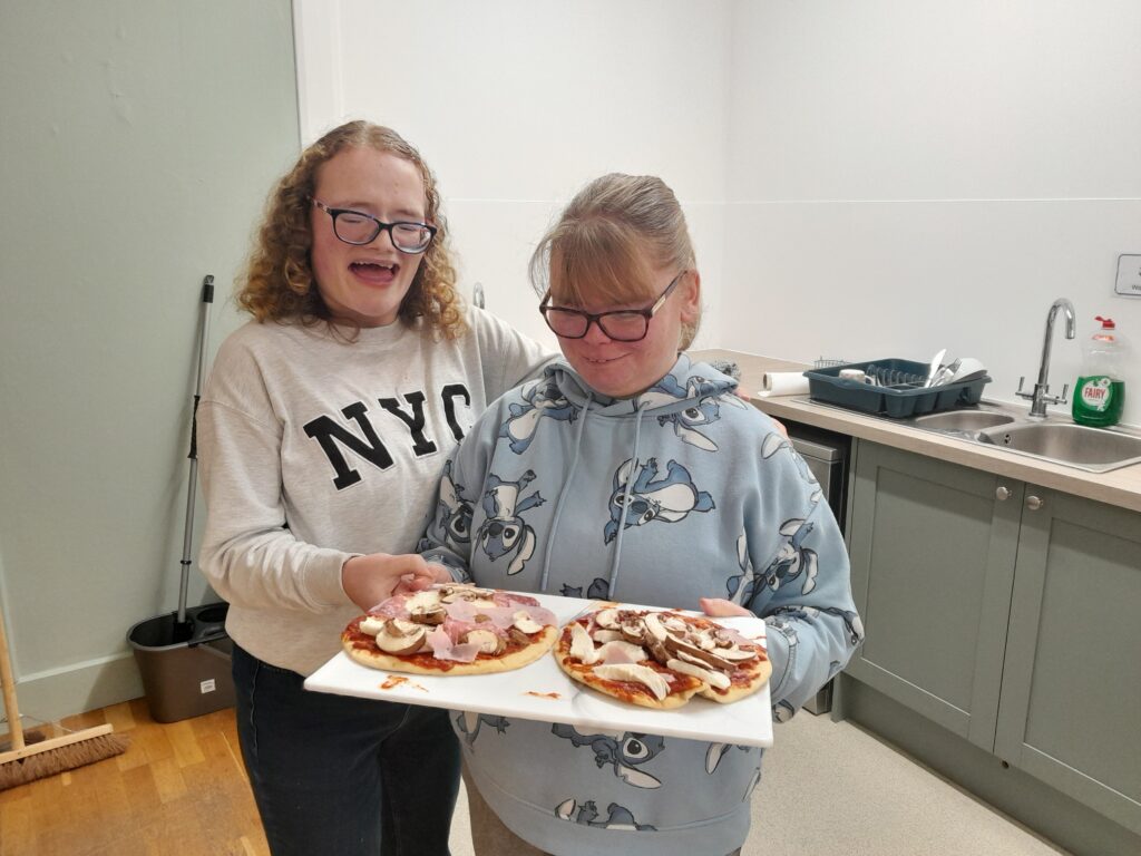 two students showing pizzas