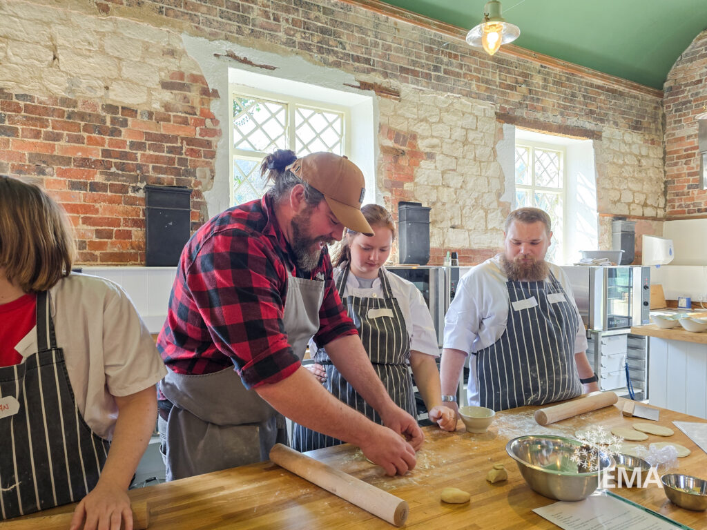 one ema tutor and three ema students making food in the moreton tearooms - rolling out dough and flattening it with a rolling pin