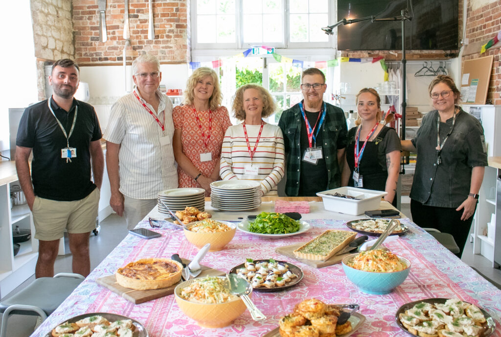 a group of people look to the camera for a photo in front of a spread of food